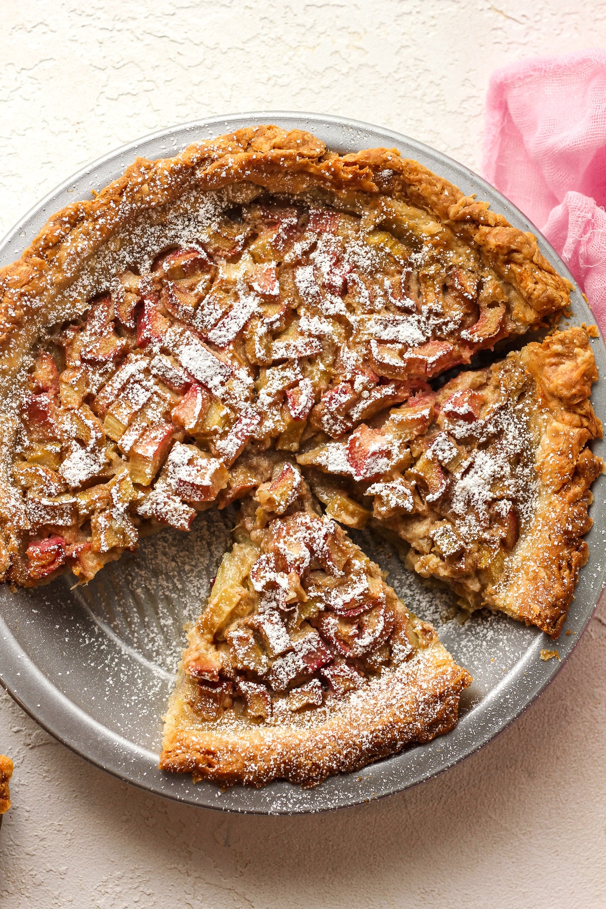 A rhubarb custard piw with two slices cut.