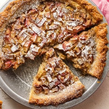 Closeup on a rhubarb custard pie with some of them cut in slices.