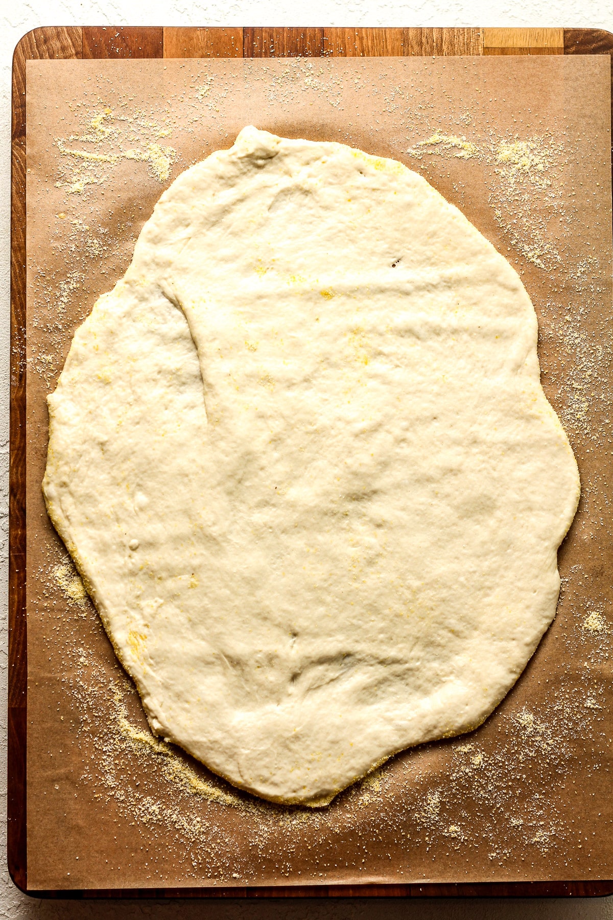 Some rolled out sourdough discard pizza dough on a piece of parchment paper.