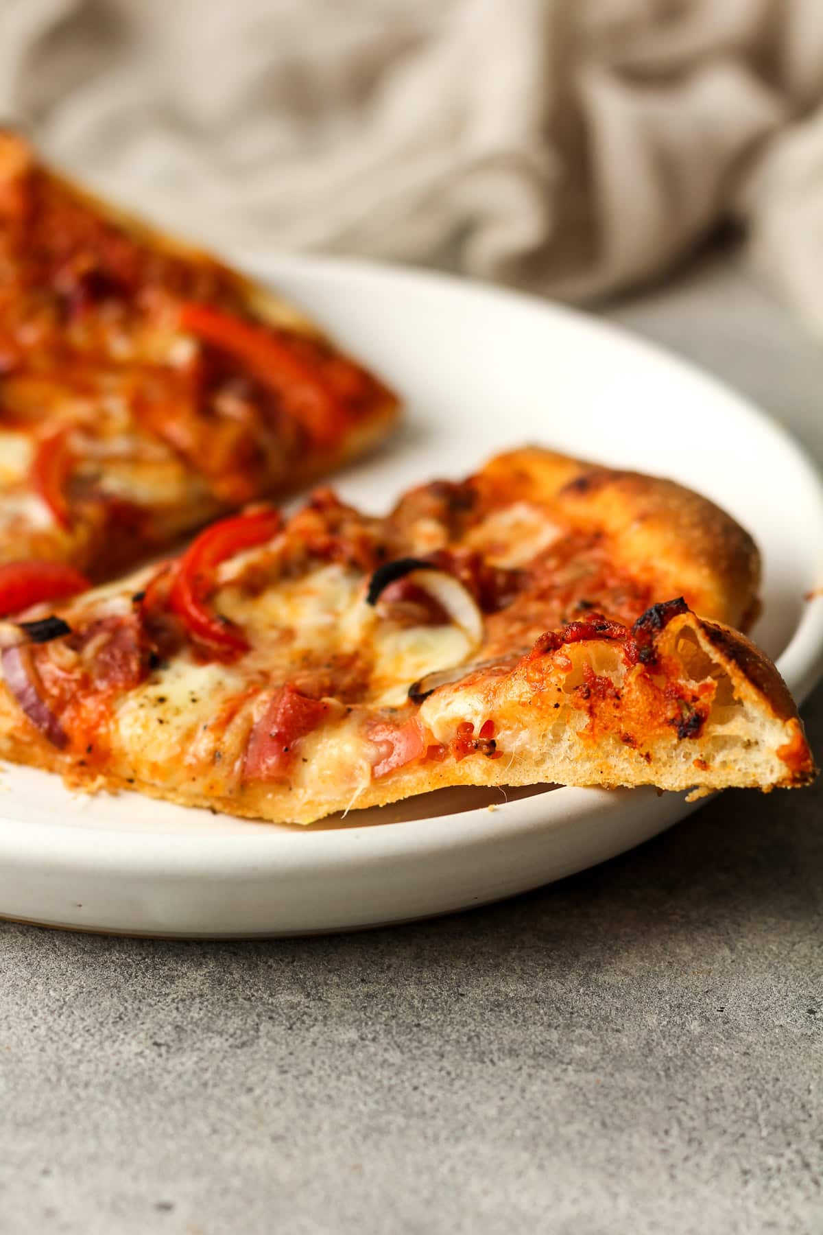 Side view of a plate of sourdough pizza with vodka sauce and toppings.