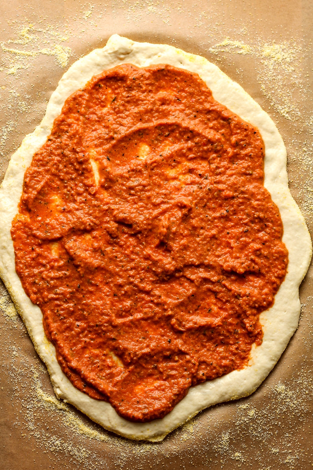 The rolled out dough with vodka pizza sauce.