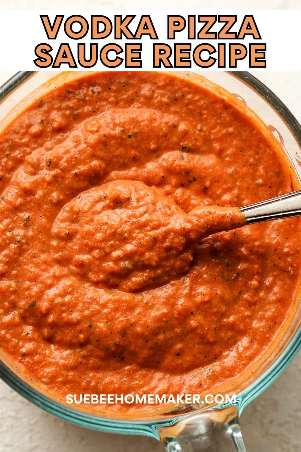 A measuring cup of the vodka pizza sauce recipe with a spoonful on top.
