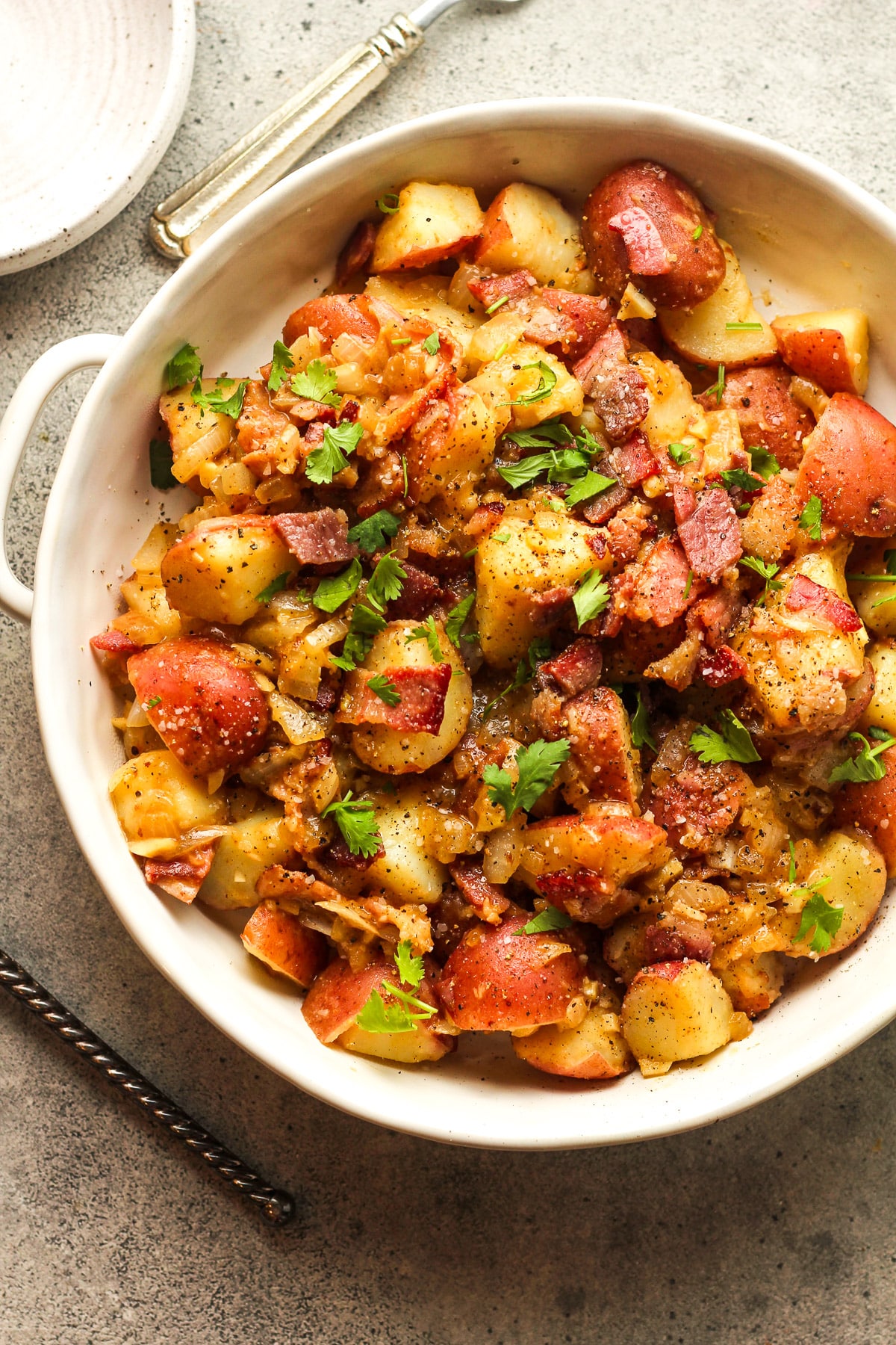 A shallow bowl of German potato salad with bacon.