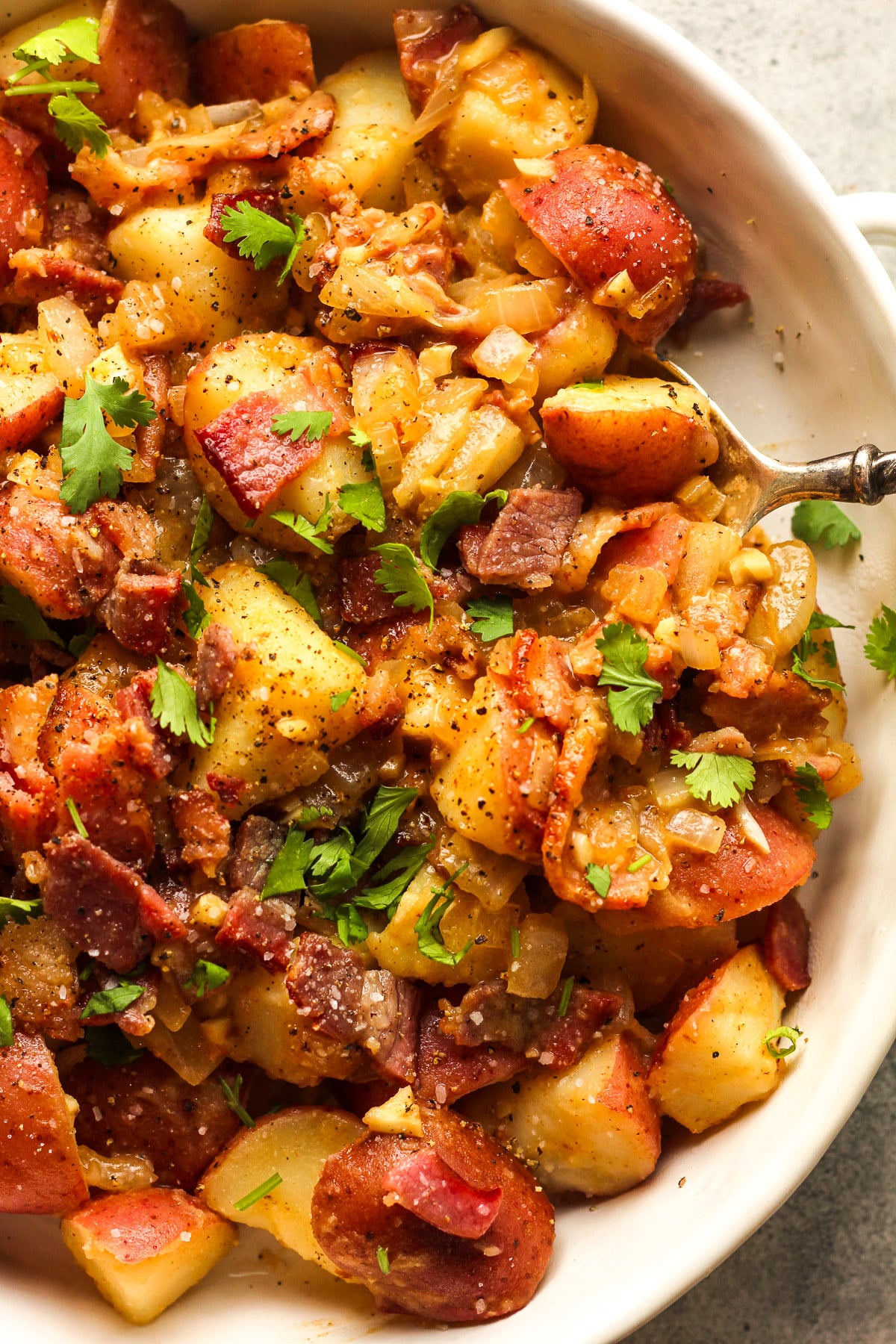 A bowl of German potato salad with chopped cilantro.