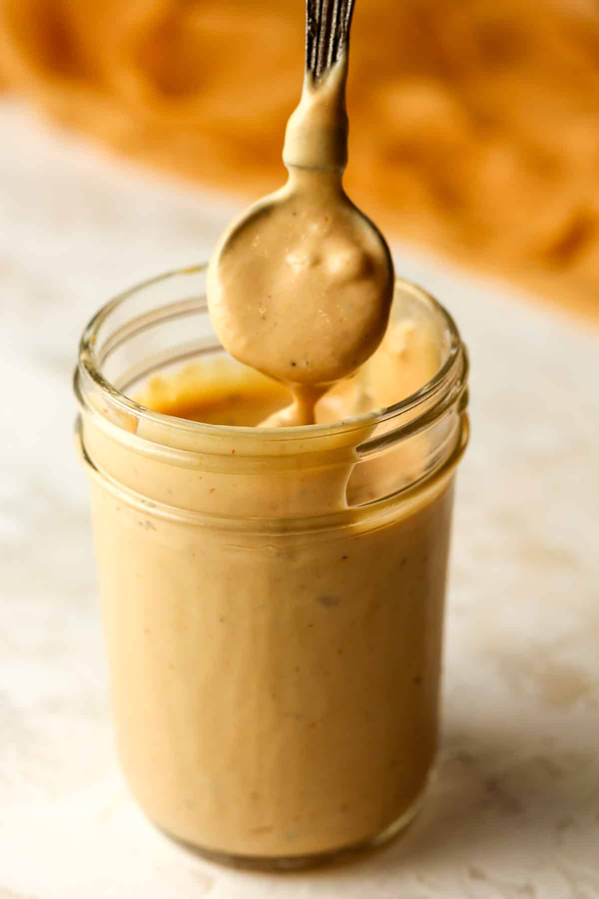 Side view of a jar of burger sauce with a spoonful pulling some up.