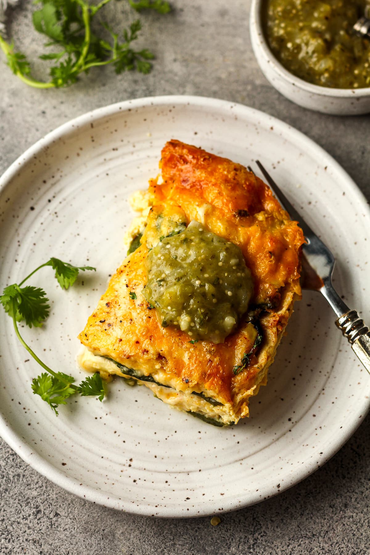 Overhead view of a serving of casserole with salsa verde on top.