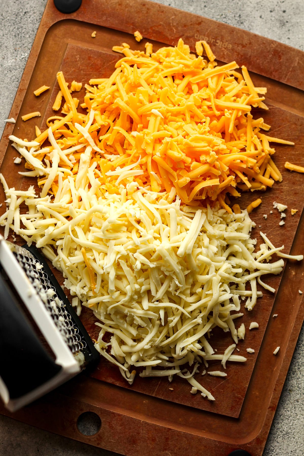 A board with the shredded cheddar and monterey cheese.