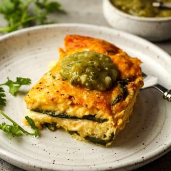 Side view of a slice of chile relleno casserole with a dollop of salsa verde.