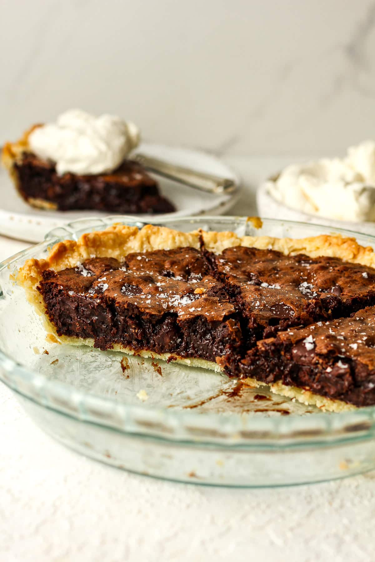 Side view of a chocolate pie and a slice in the background.