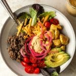 A deconstructed burger bowl with pickled red onions.