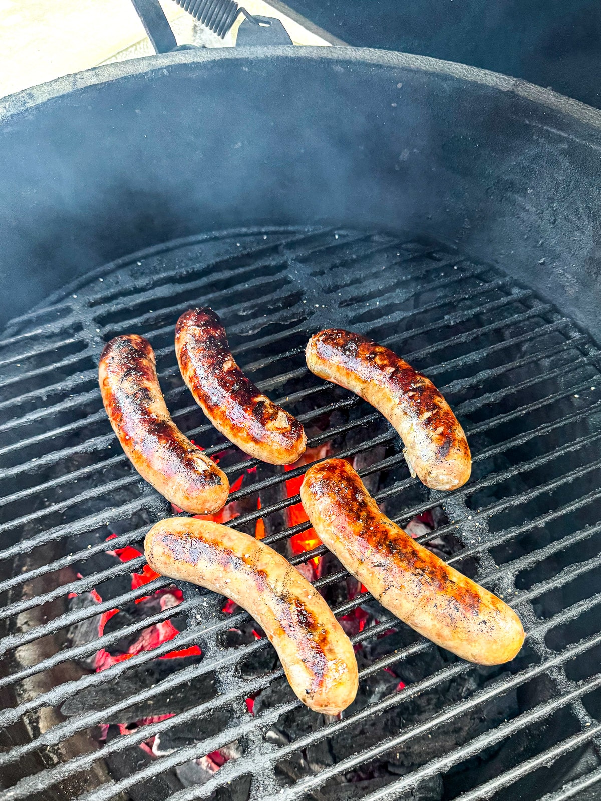 The grilled brats on the grill grates.
