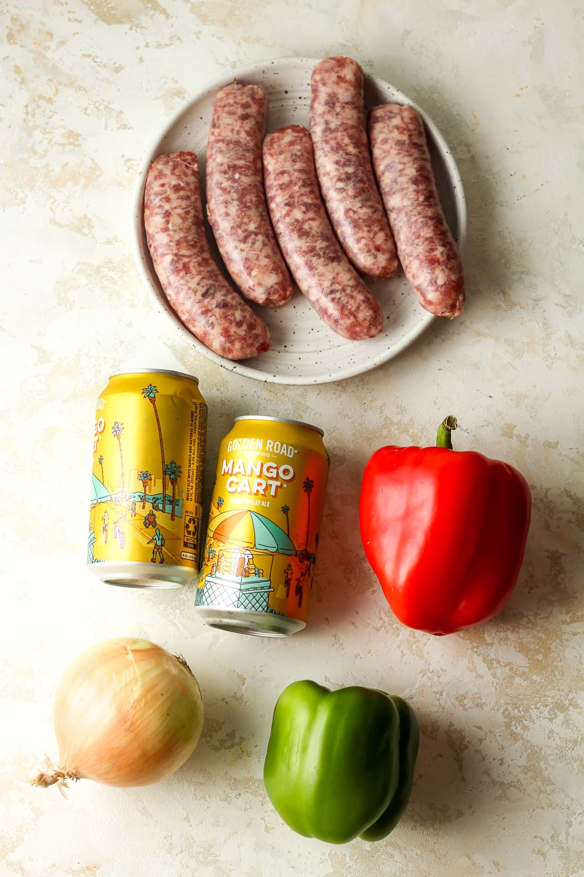 Ingredients for grilled beer brats - including brats, beer, bell peppers, and onion.