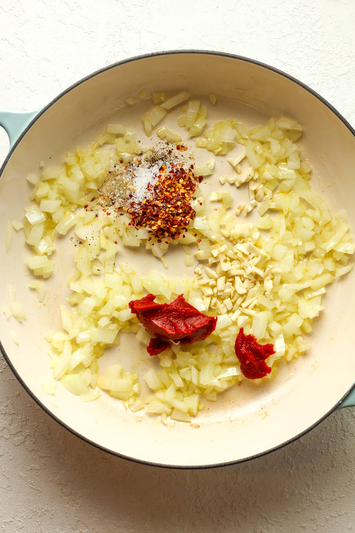 The braiser with sauteed onions and the garlic, tomato paste, and seasonings on top.