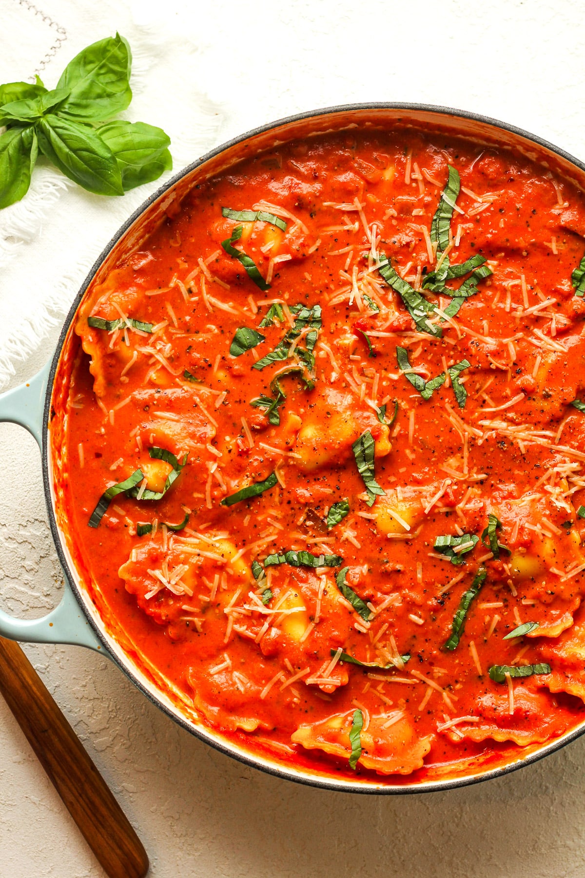 A large braiser of ravioli alla vodka with fresh basil.