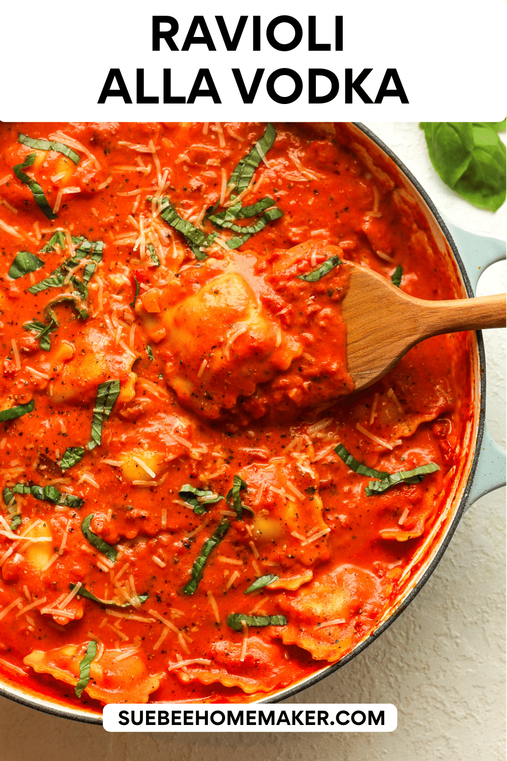 A shallow braiser with ravioli alla vodka and a wooden spoon lifting some up.
