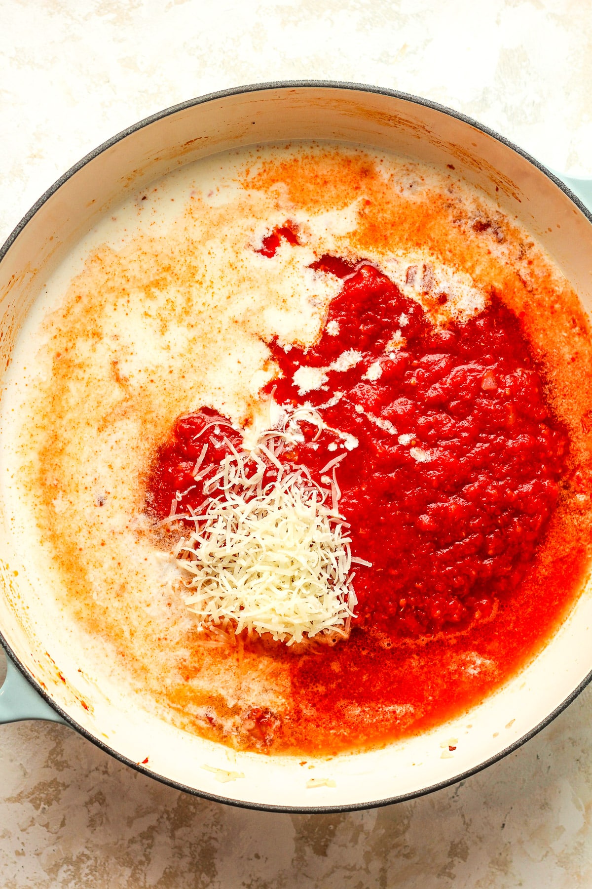 A shallow pan of the ingredients after adding the tomatoes, cream, and parmesan.