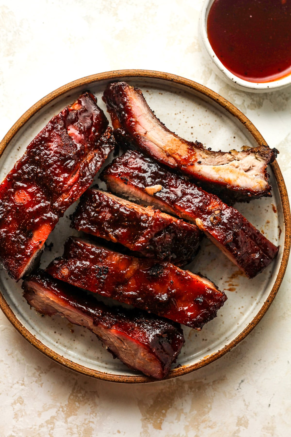 A plate with several sliced baby back ribs with sauce.