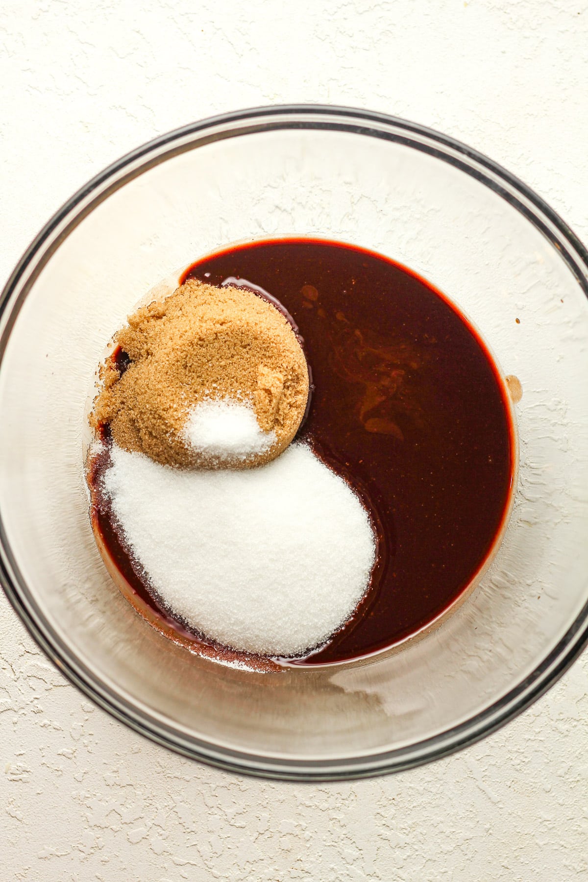 A glass bowl of the melted butter and chocolate topped with sugars.
