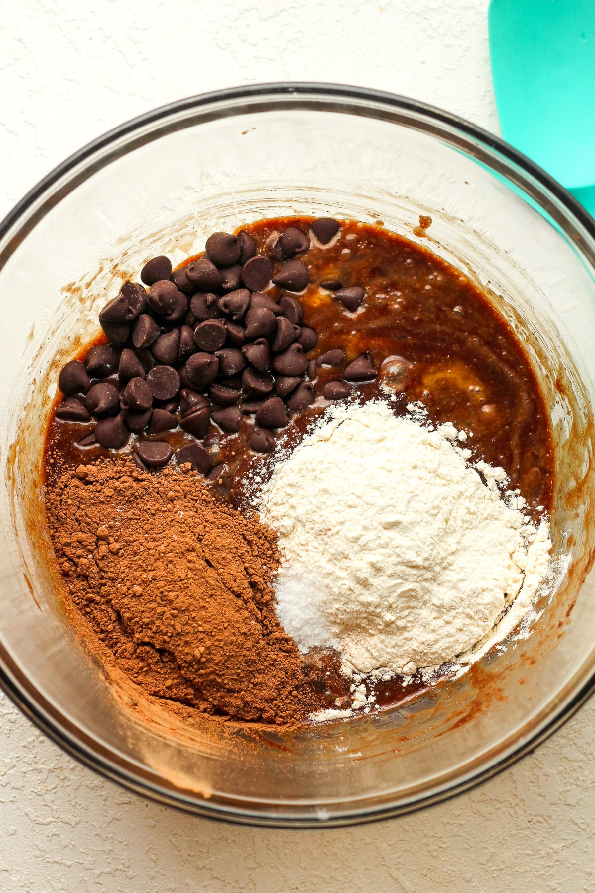 A bowl of the brownie batter with the dry ingredients on top.