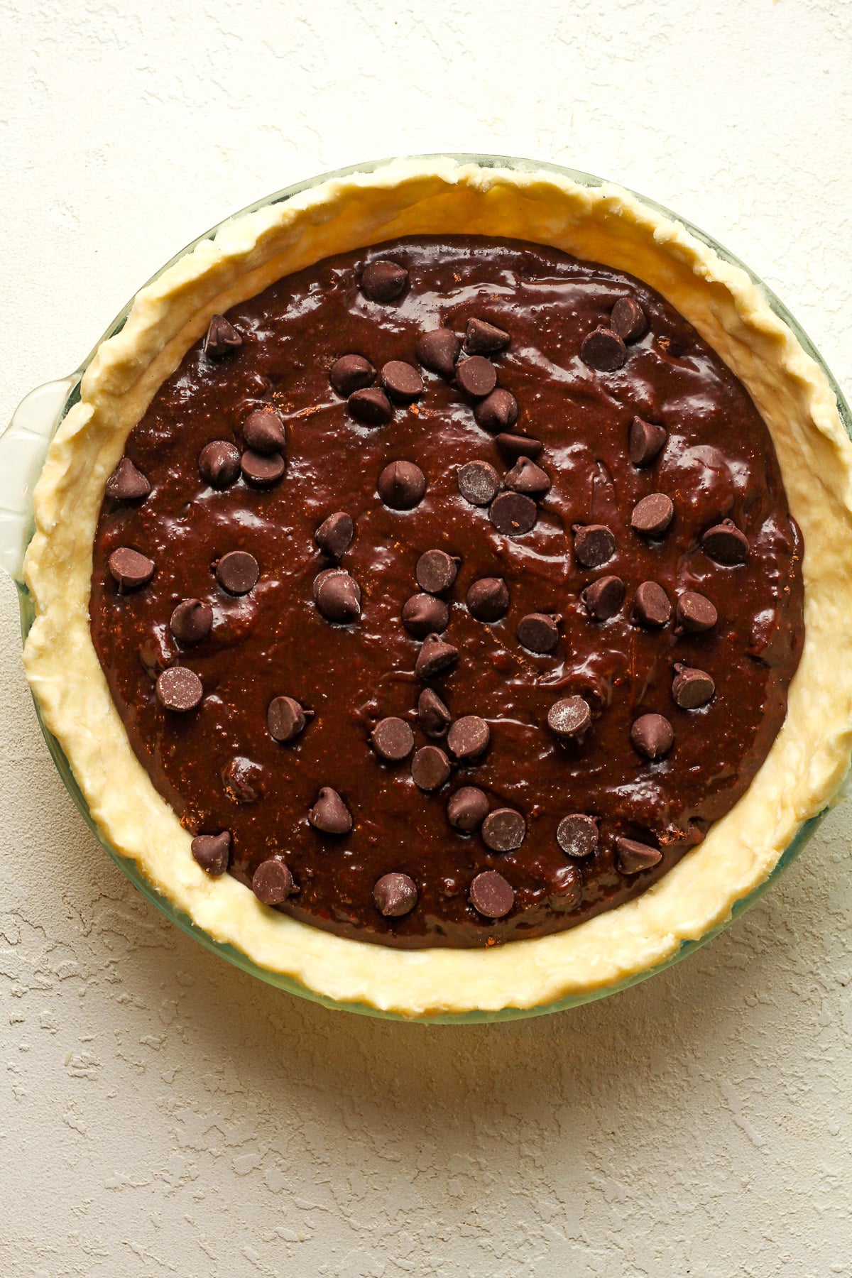 The pressed pie crust in a pie plate with the brownie batter inside.