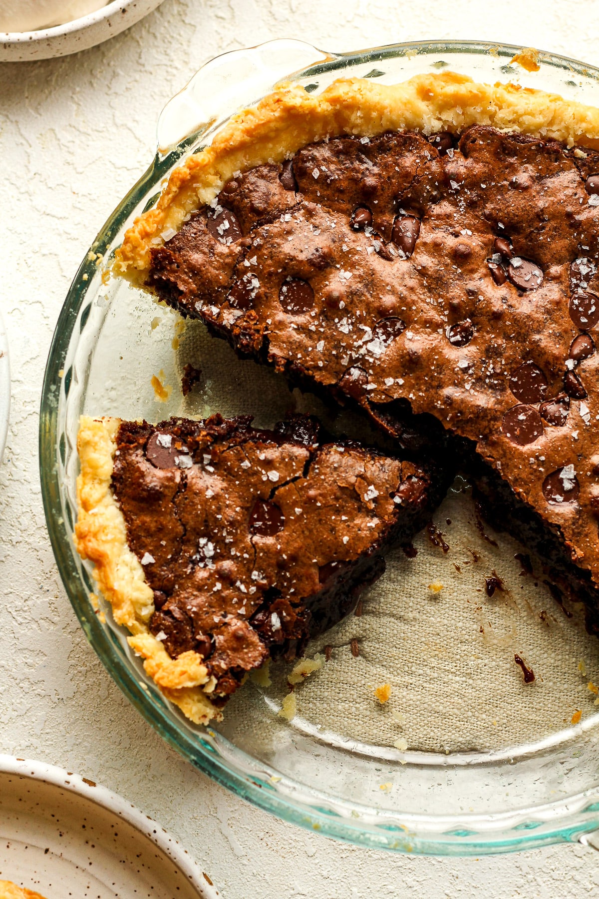 Overhead view of a brownie pie in a flaky pie crust, with some slices removed.
