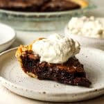 Side view of a slice of chocolate brownie pie with cool whip on top.