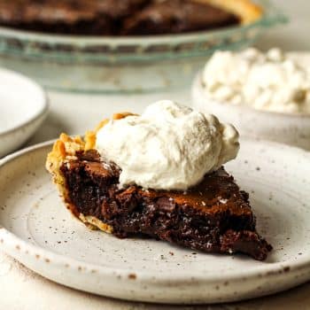 Side view of a slice of chocolate brownie pie with cool whip on top.