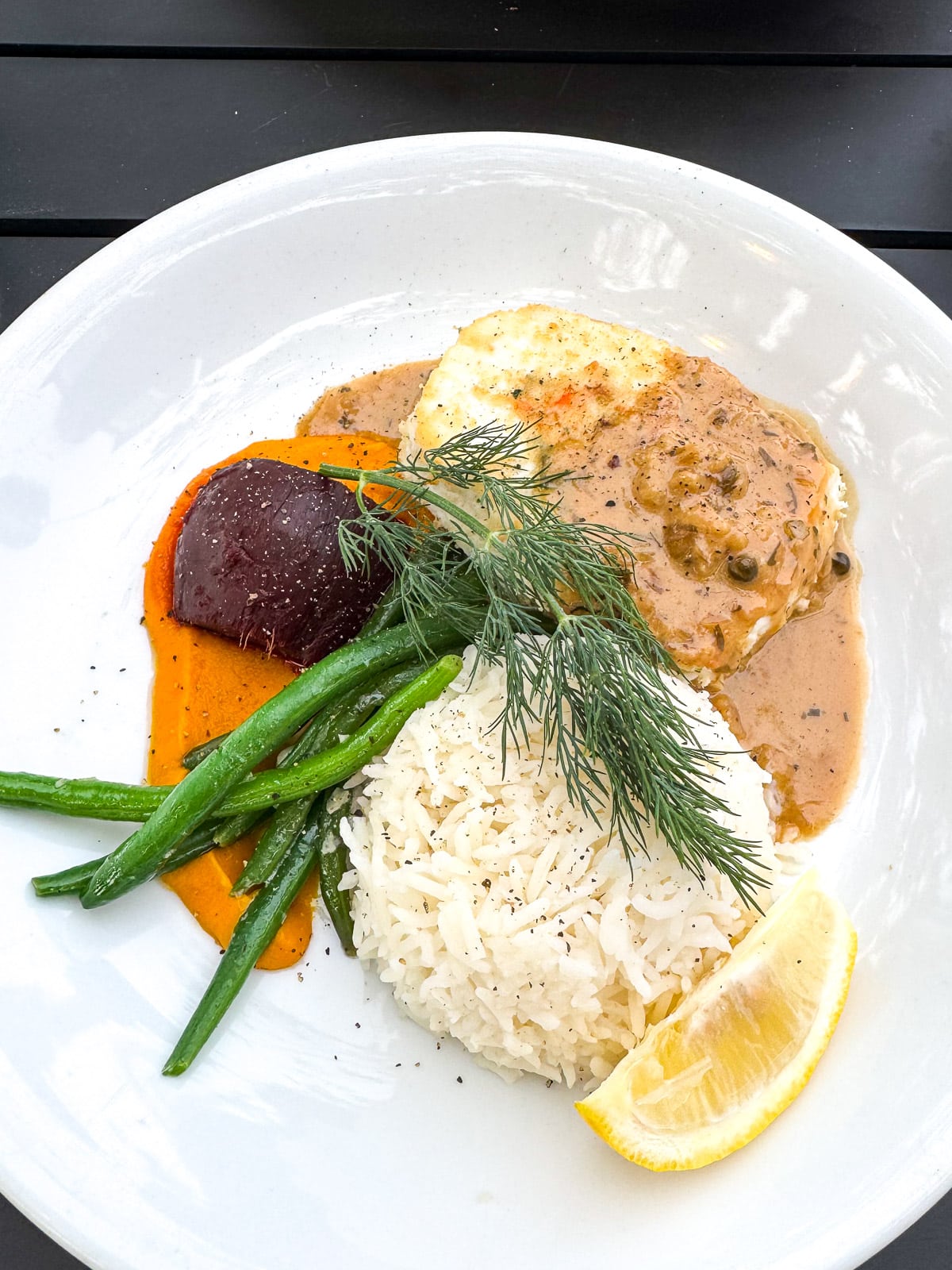 A plate of halibut with rice and veggies.