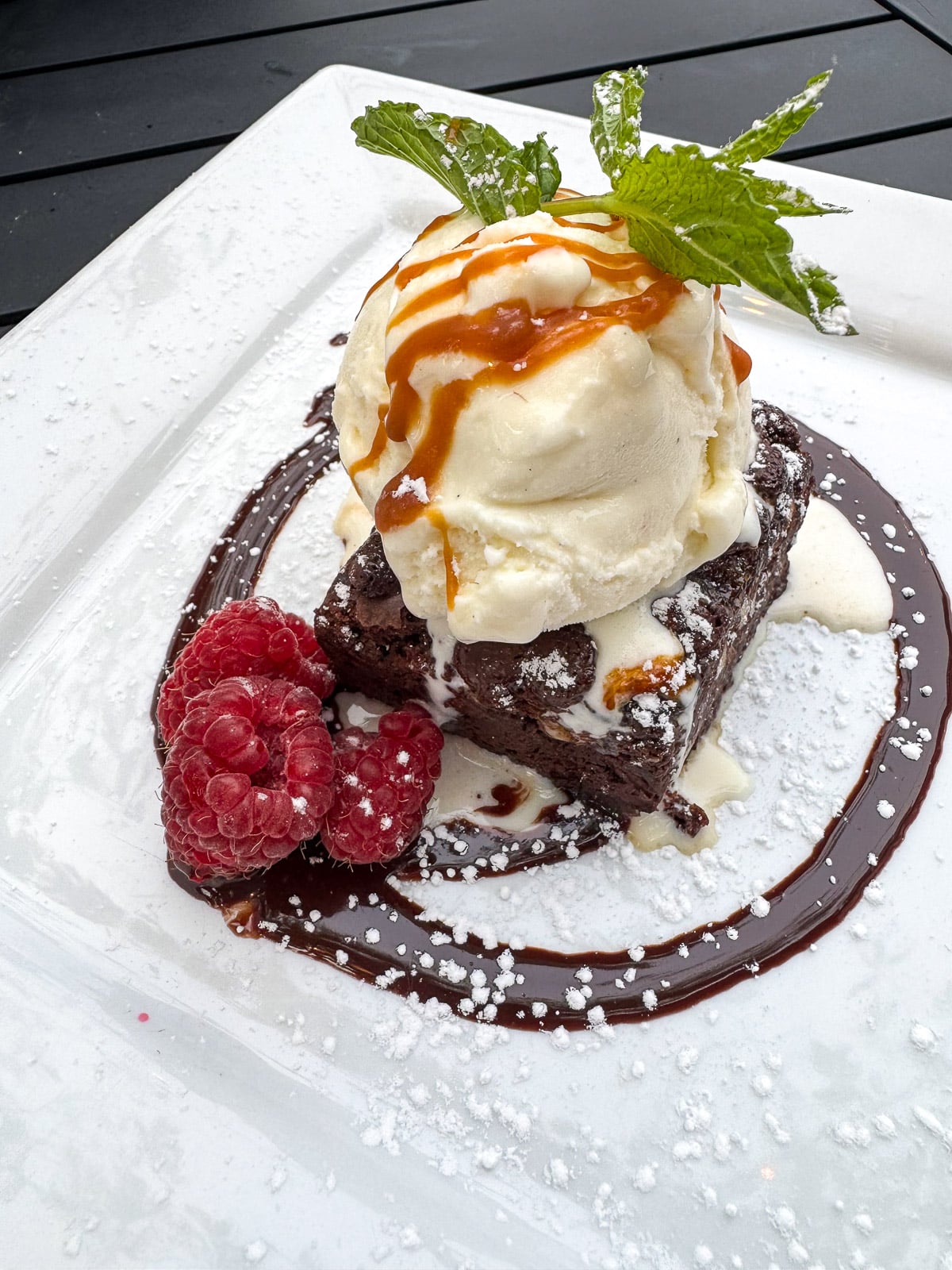 A pic of brownie with ice cream and caramel.