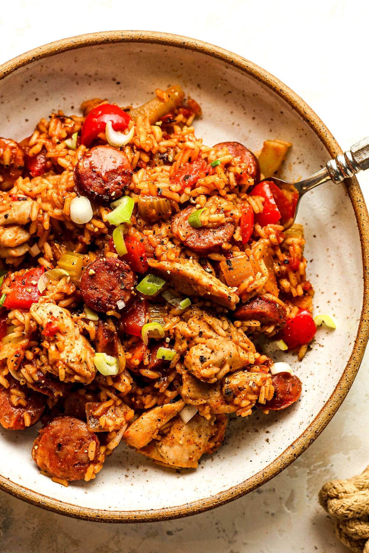 A bowl of chicken and sausage jambalaya with a fork.