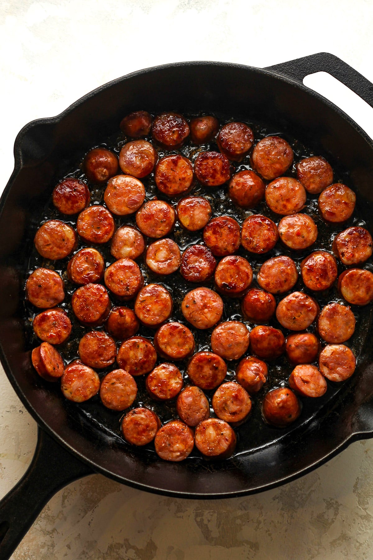 A skillet of browned andouille sausage rounds.