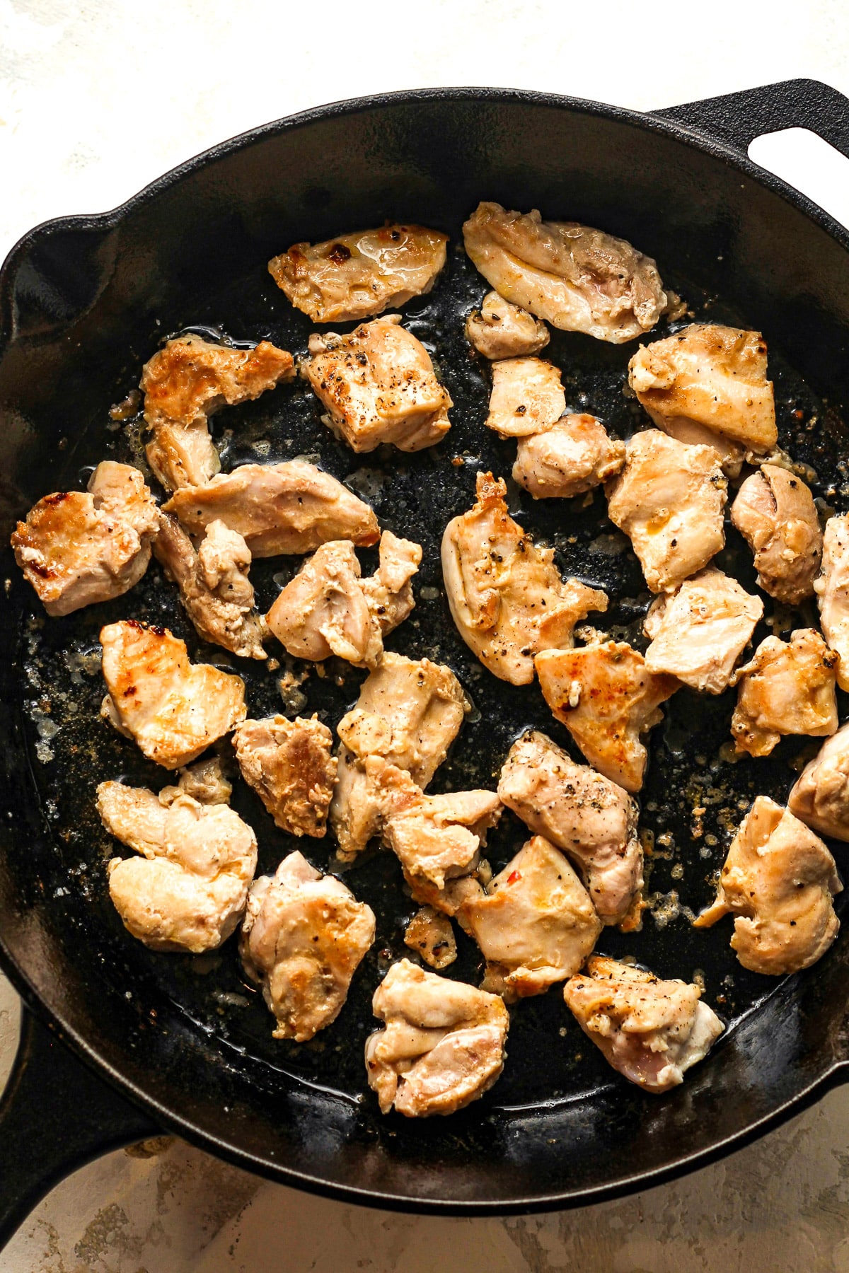 A skillet of browned chicken thighs.