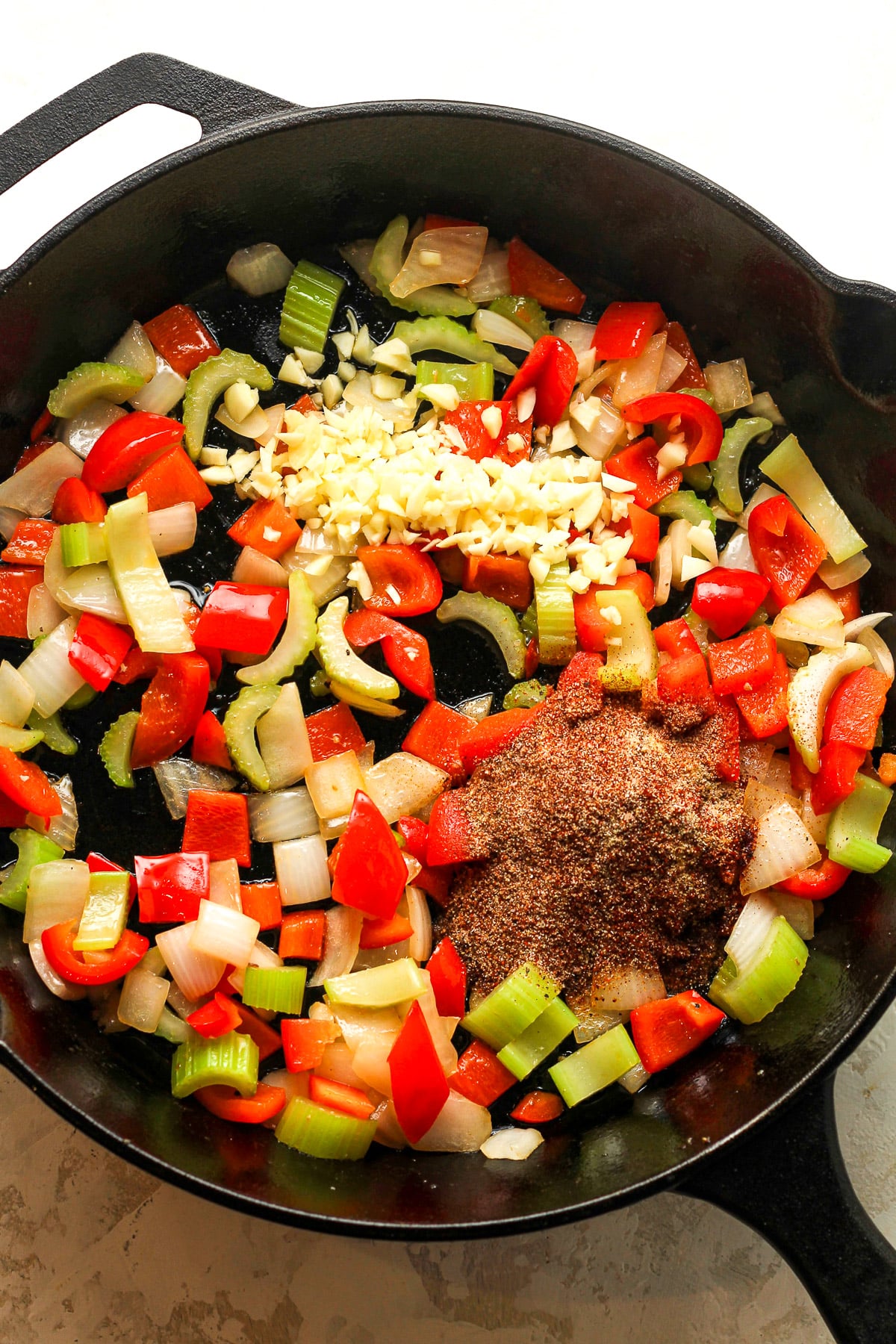 A skillet of the sauteed veggies plus garlic and seasonings on top.