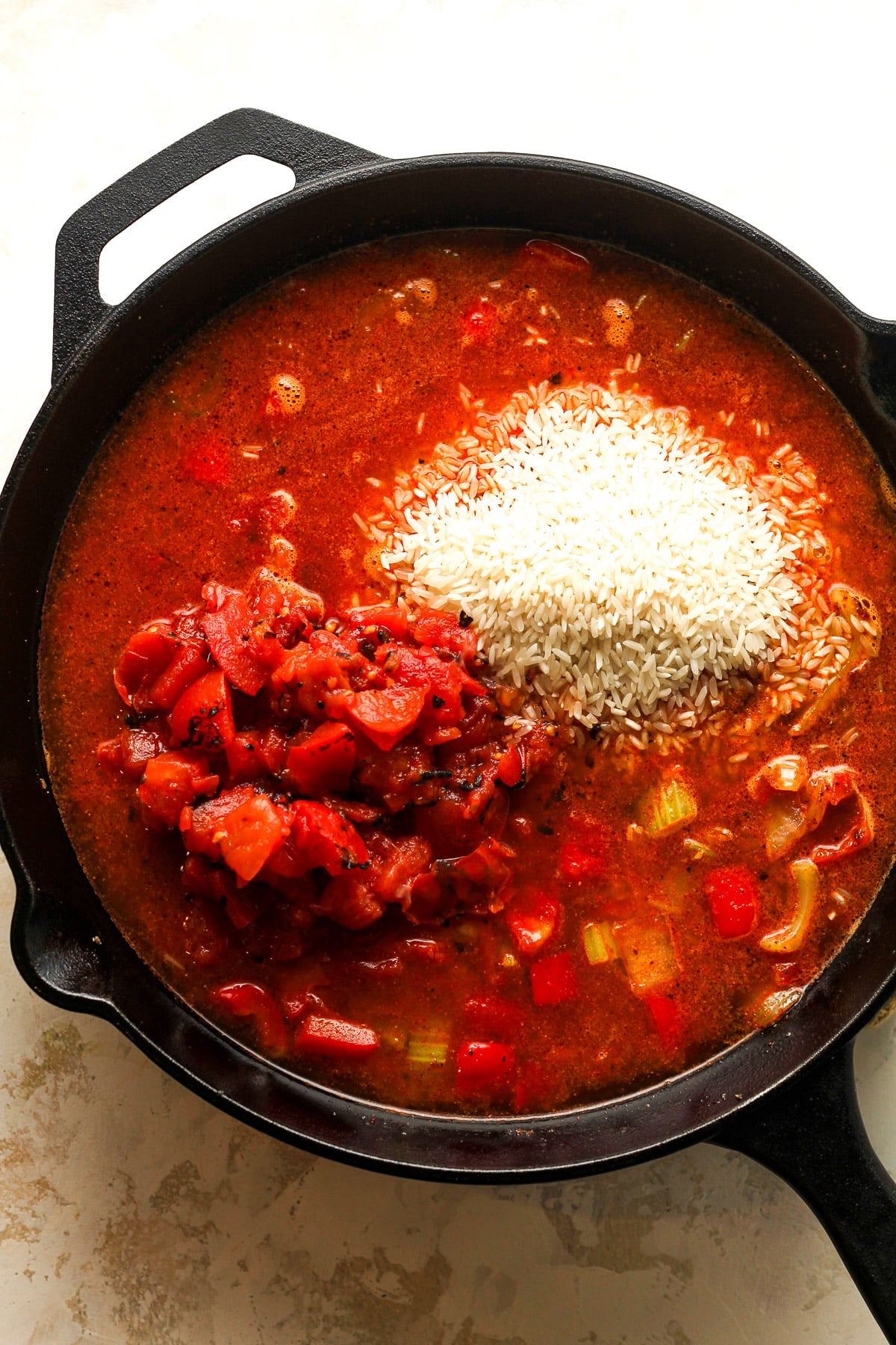 A skillet of the jambalaya after adding the rice and liquids.