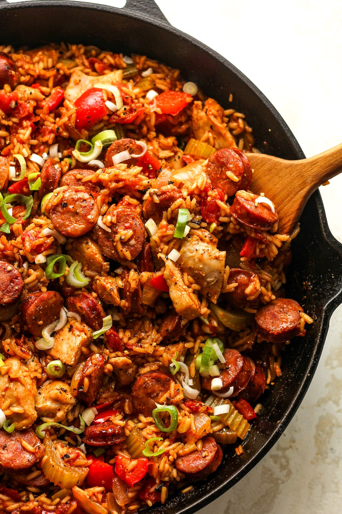 Closeup on a skillet of jambalaya. with a wooden spoon.