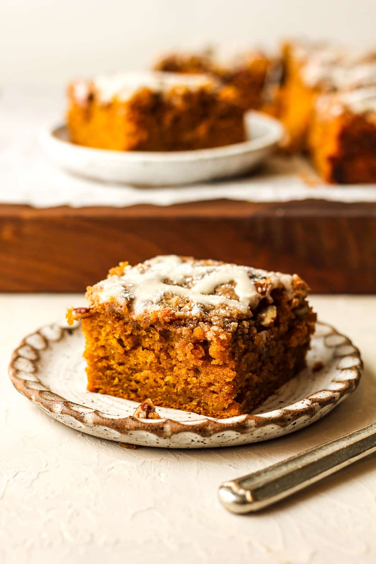 A small plate of pumpkin crunch coffee cake in front of the remaining cake.