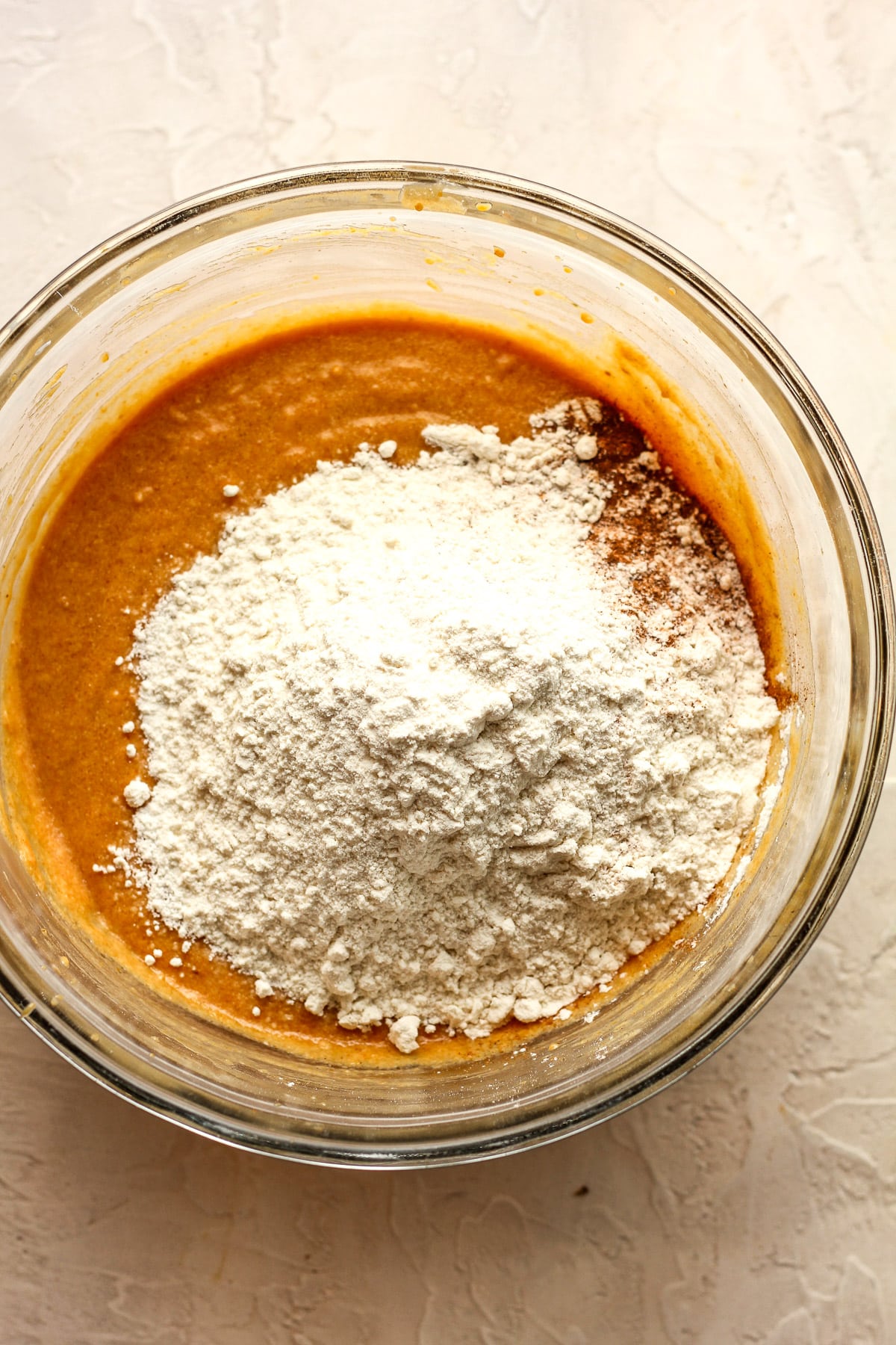 A bowl of the wet mixture topped with the dry ingredients.