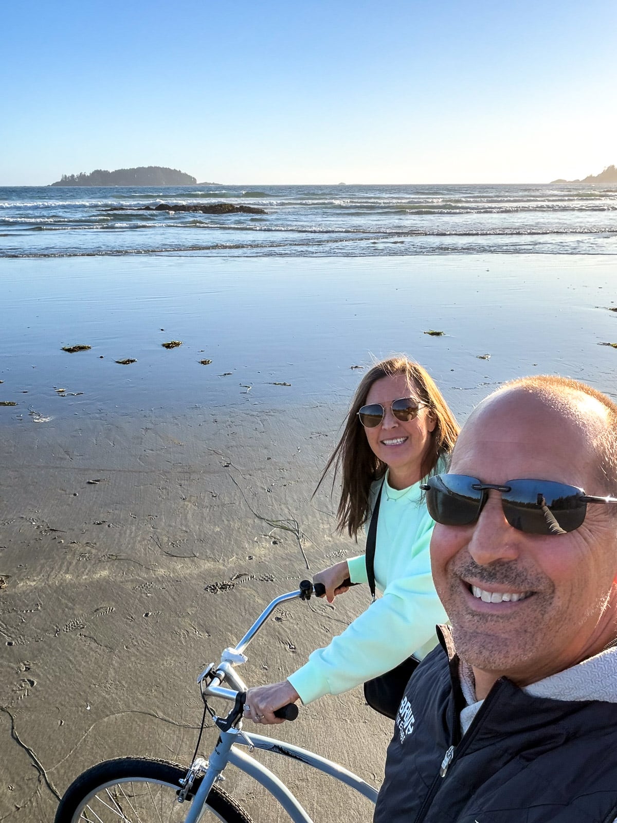 Sue and Mike riding bikes on the beach in Tofino.