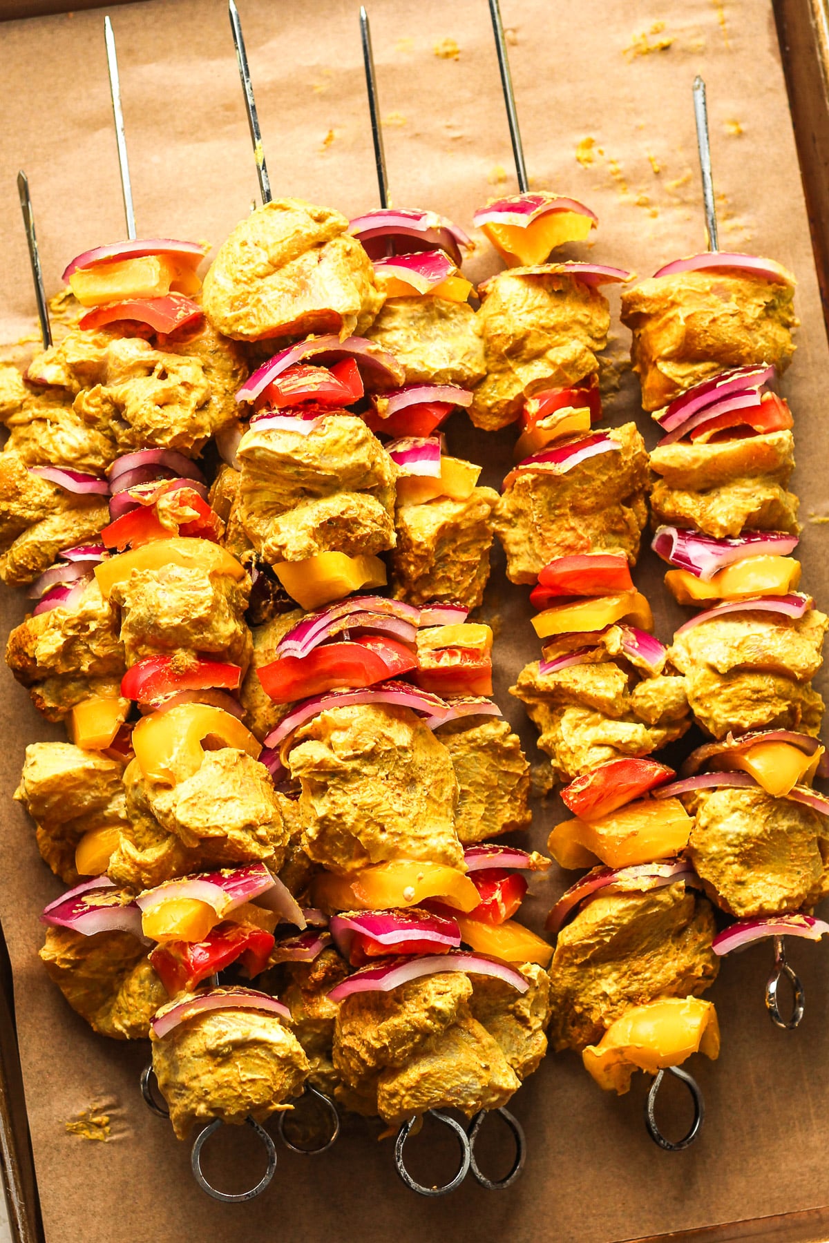 Overhead view of some prepared butter chicken kabobs with veggies.