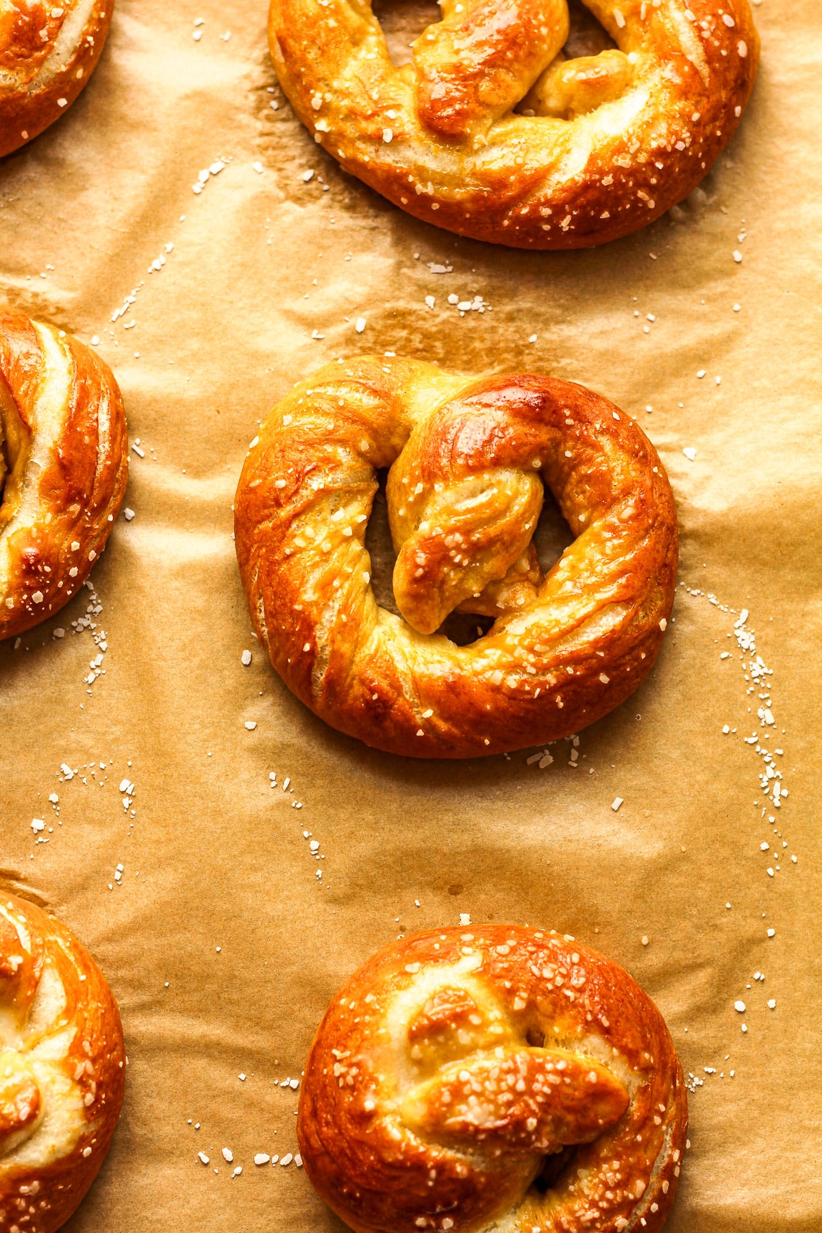 A sheet pan of baked homemade soft pretzels with salt.