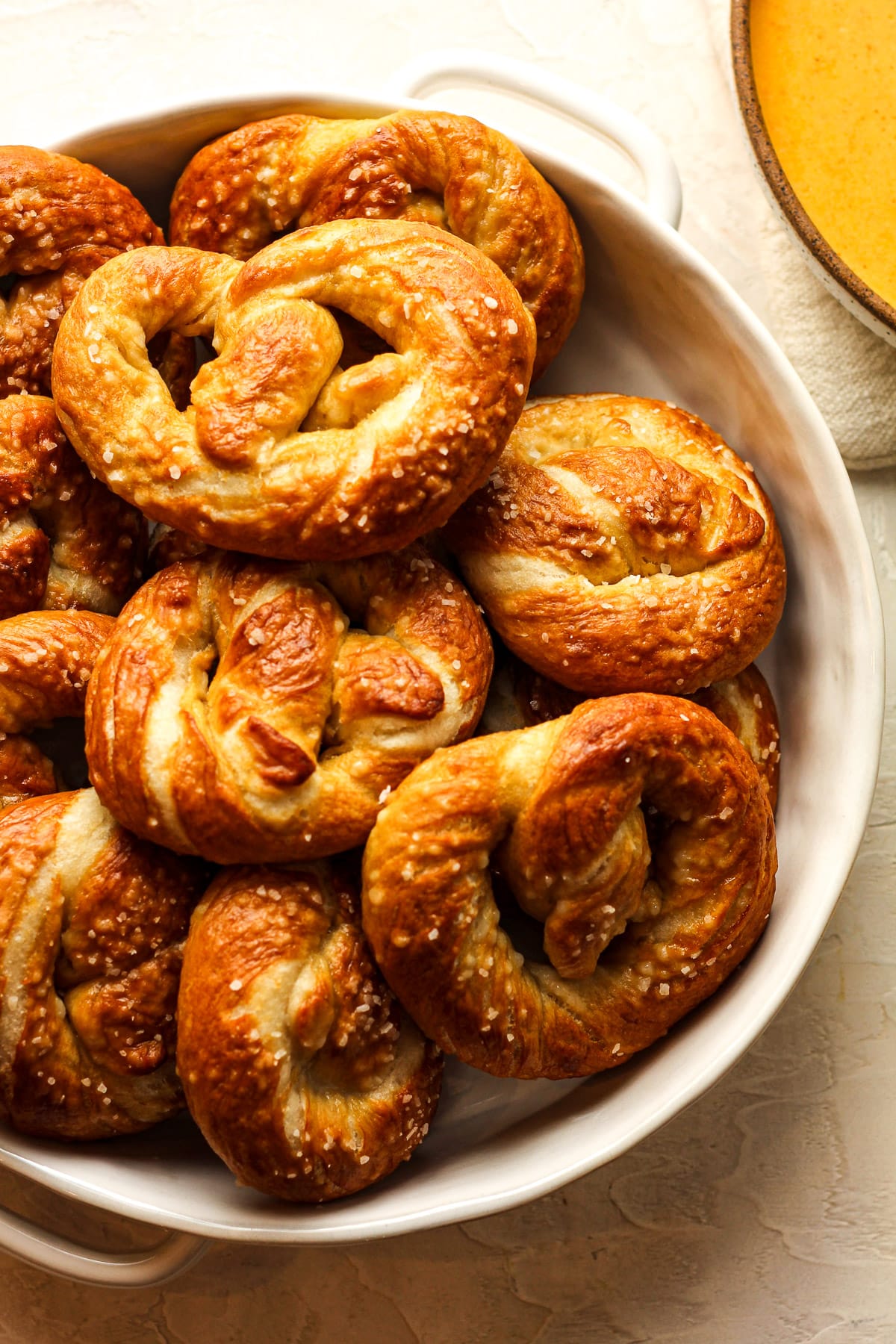 A bowl of homemade soft pretzels next to a bowl of cheese sauce.