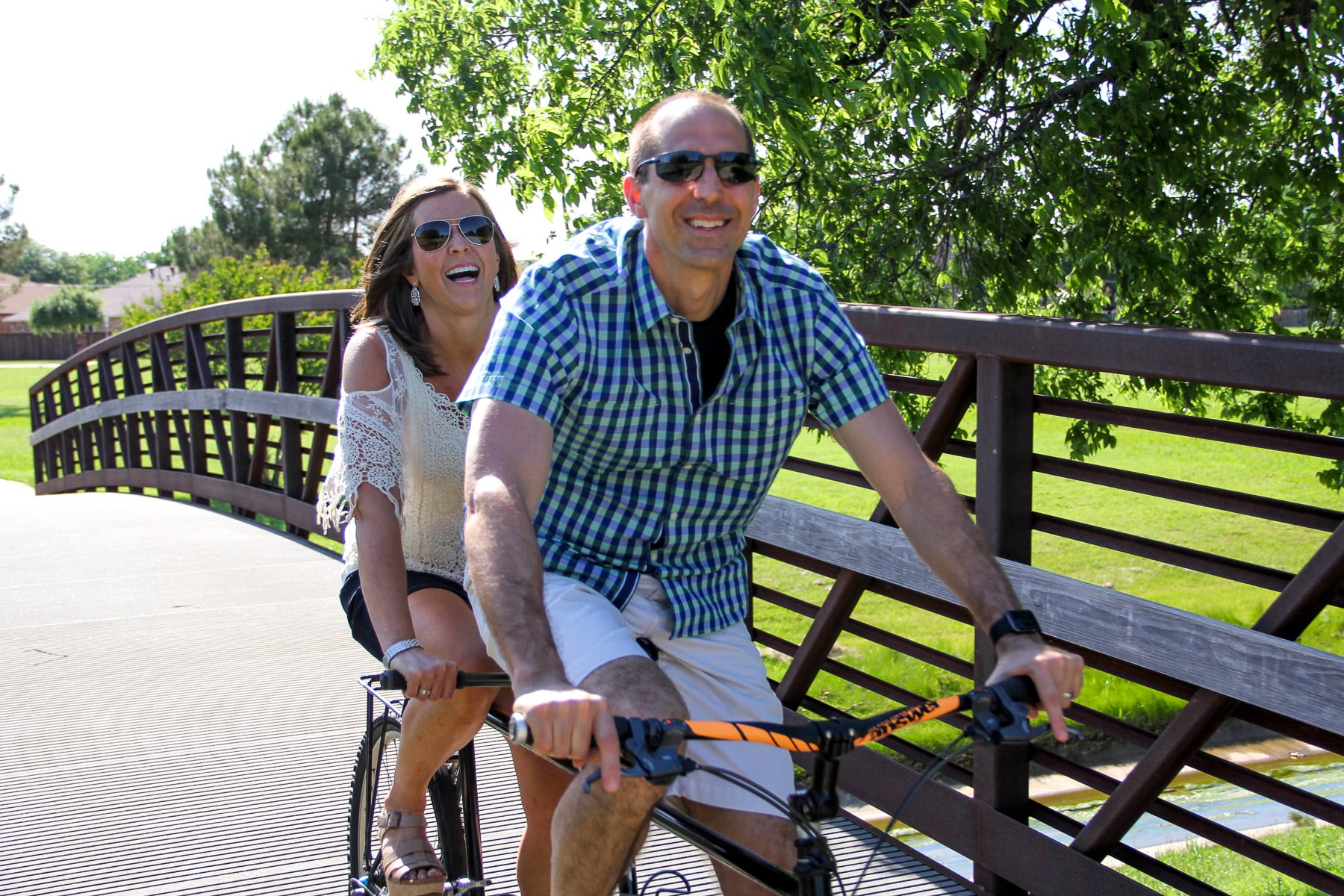 A photo of Mike and I on a tandem bike riding over a bridge in a local park.
