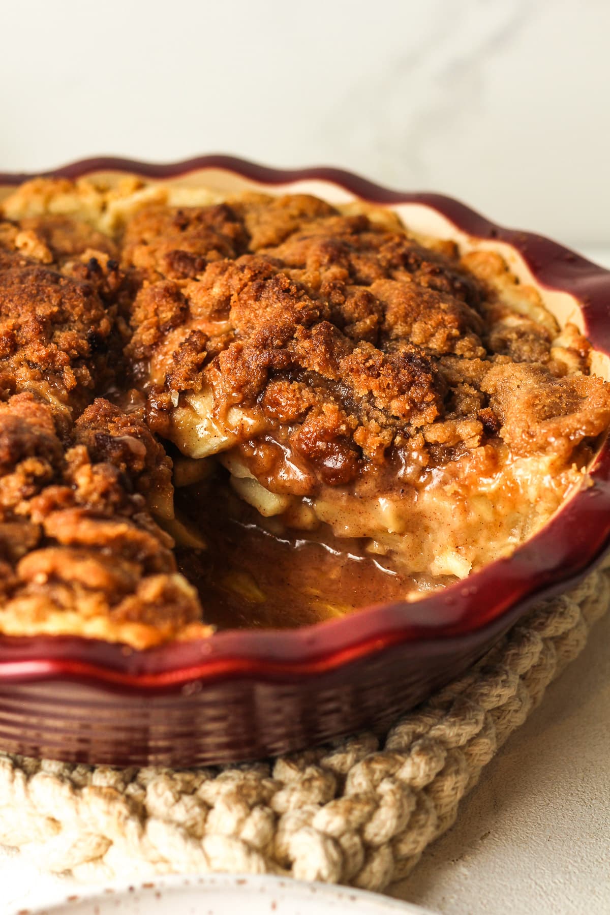 Side view of an apple crumble pie with a slice removed.
