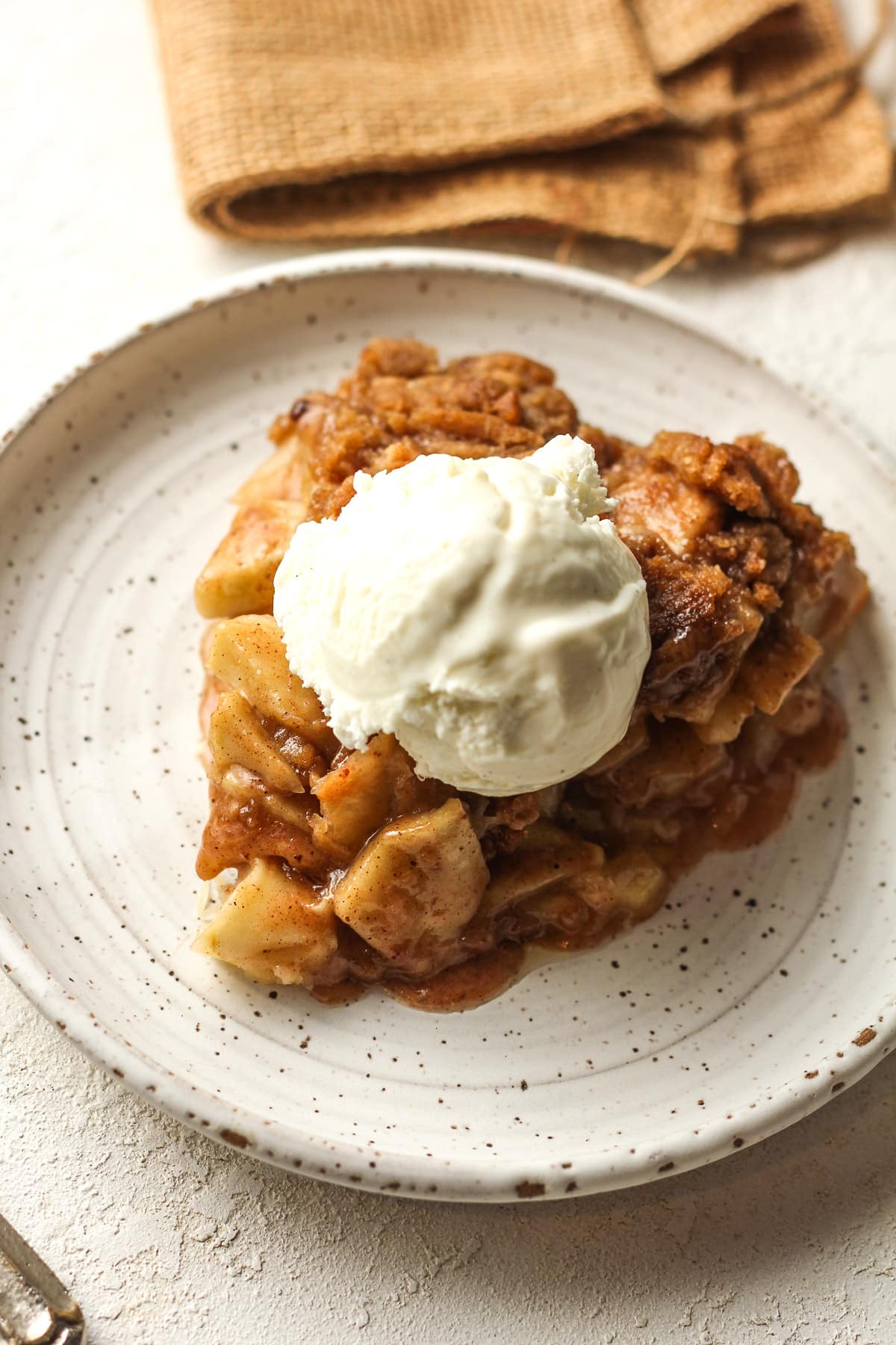 Overhead view of a slice of apple crumble pie with ice cream.