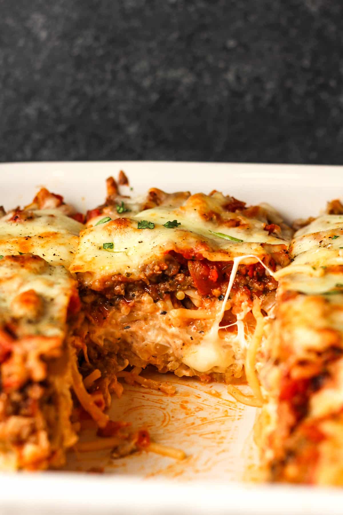 Side view of a slice of the casserole inside the baking dish.