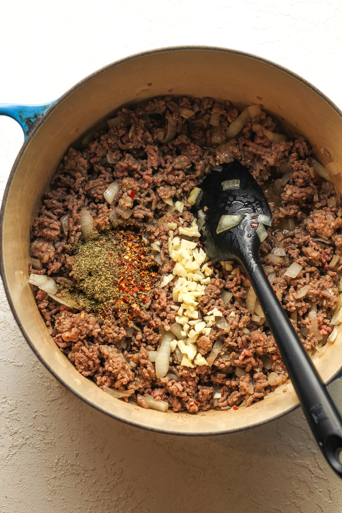 A pot of the browned meat with the garlic and seasonings on top.