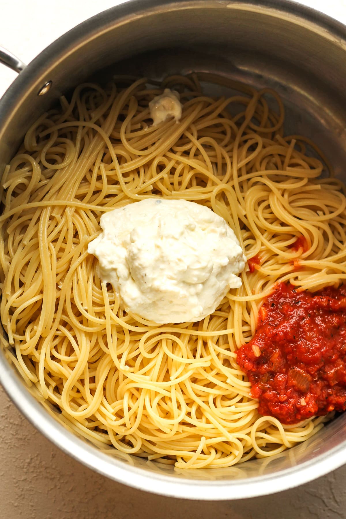 A pot of spaghetti with some of the cheese and some of the marinar.