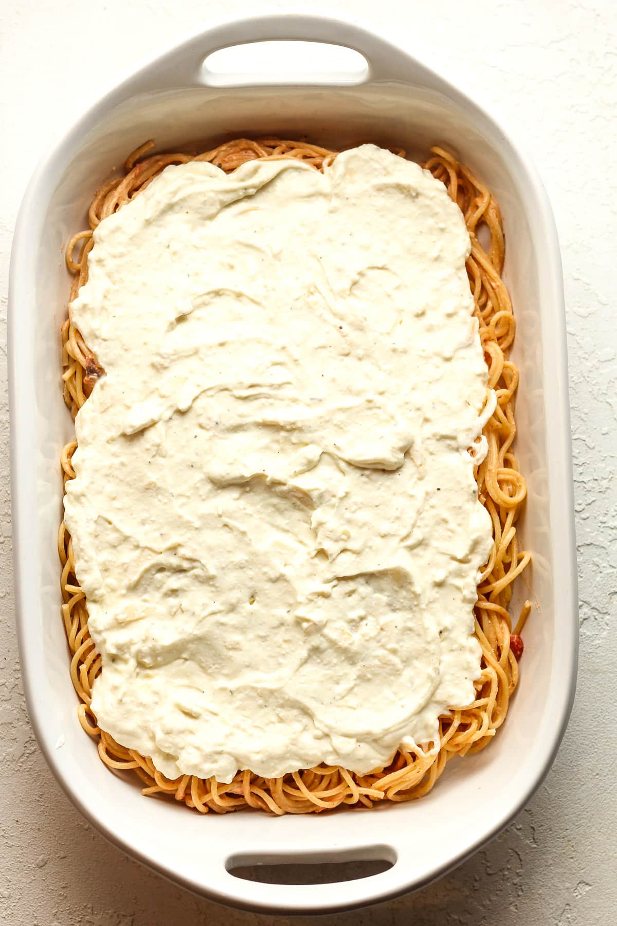 A casserole of the spaghetti topped with the cheese layer.