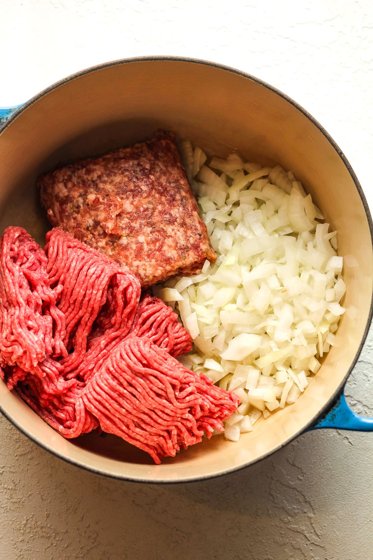 A pot of the onions, ground beef, and sausage before cooking.