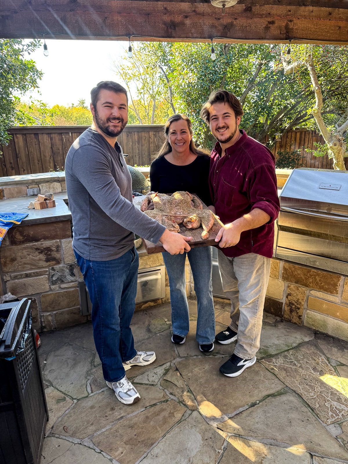 Josh, me, and Zach on the deck holding a prepped turkey to go on smoker.